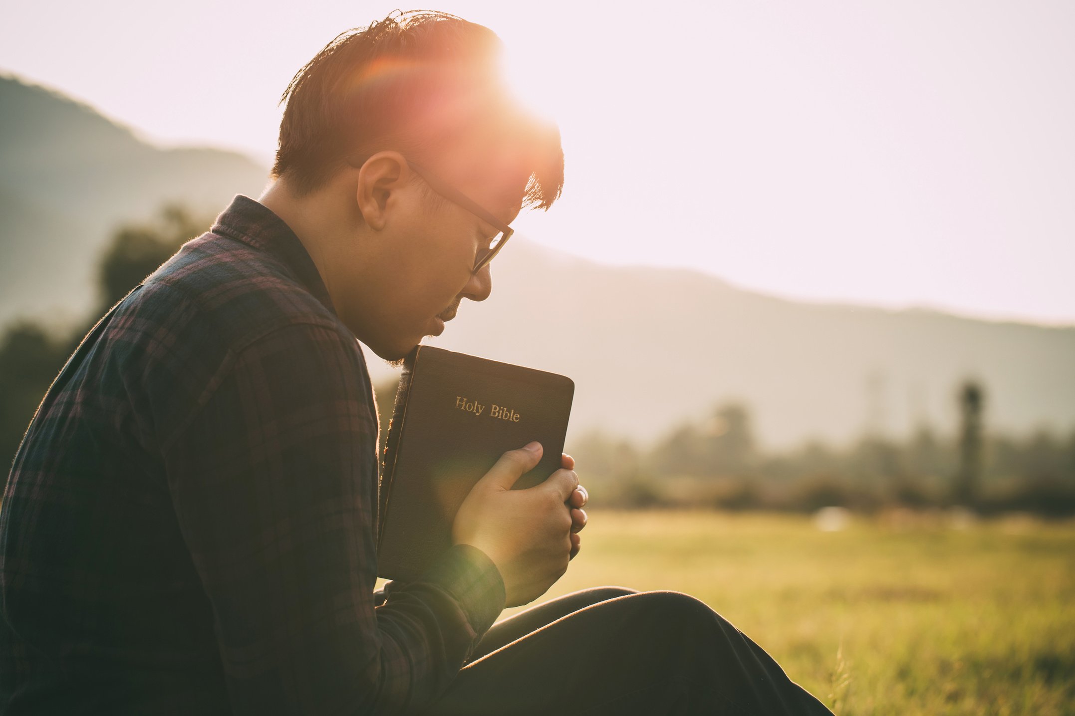 Man with Bible Praying to God Outdoors